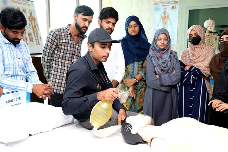 An instructor demonstrates bag-mask ventilation on a manikin while participants watch