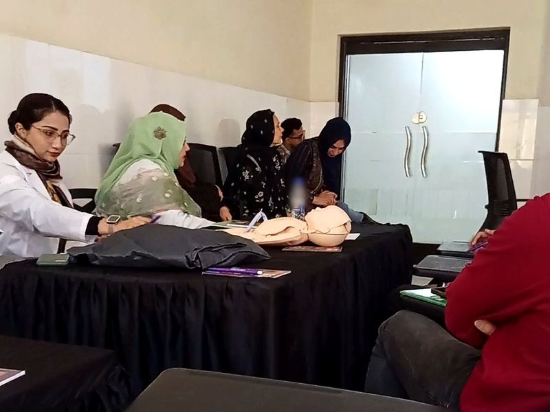 Participants seated at a table with manikins, practising and taking notes